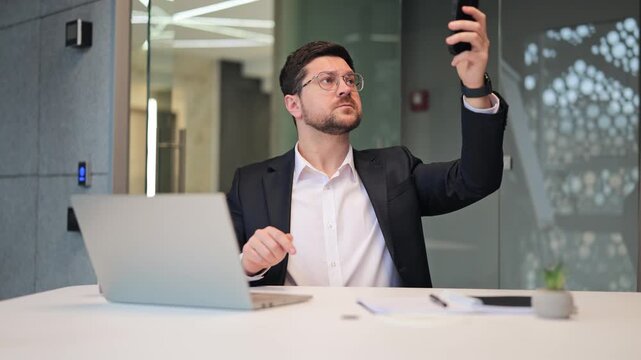 Frustrated male entrepreneur looking at smartphone in anger due to no Wi-Fi and cellular connection. Stressed businessman shouting and gesturing because of lost internet signal in the office.