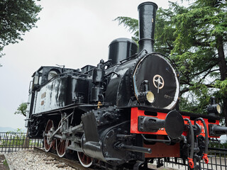 Obraz premium Black Steam Locomotive SNFT 1 Displayed On Rail Tracks With Red Wheels , Brescia, Italy