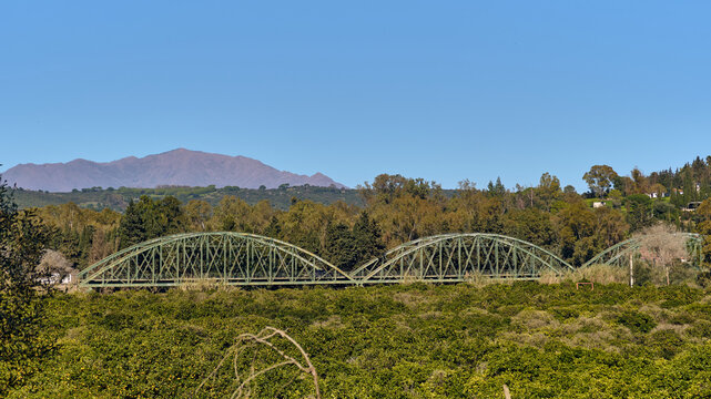 Rural Landscape And Infrastructure In Guadiaro Spain A Green Metal Bridge Lush Vegetation And Distant Mountains Under A Clear Blue Sky Costa Del Sol