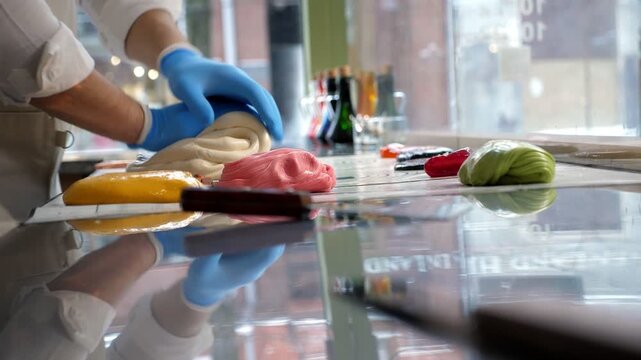 A close-up shot of the process of making caramel candies and lollipops in a modern candy shop, where a pastry chef uses scissors to cut off liquid, stretchable caramel. Handmade lollipops.