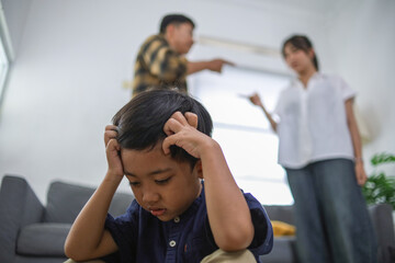 Obraz premium Emotionally Distressed Child Covering Ears with Parents Arguing in Background