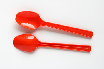 Two Red Plastic Spoons laid out against a clean white background.