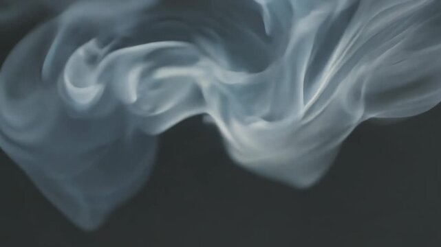 Smoke billows and swirls in a continuous flow against a dark background, creating dynamic shapes and patterns that evolve over time in a mesmerizing visual display