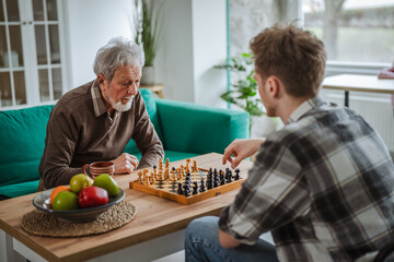 Senior man and young man playing chess