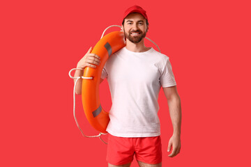 Young happy male lifeguard with ring buoy ring on red background © Pixel-Shot