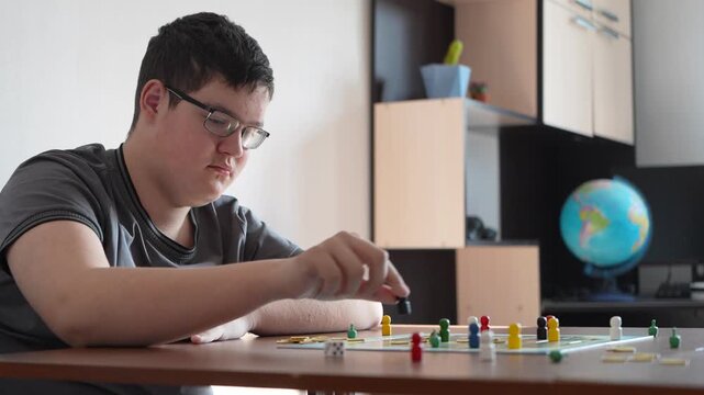 A teenager plays a domino chain reaction game at a table, carefully setting up tiles in a row.