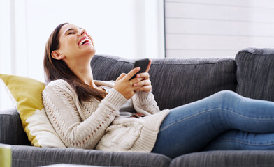 Obraz premium Relax, girl and laugh with phone on sofa for internet meme, funny social media post or weekend break. Happy, person or scroll on smartphone in home for streaming subscription, comic status or texting