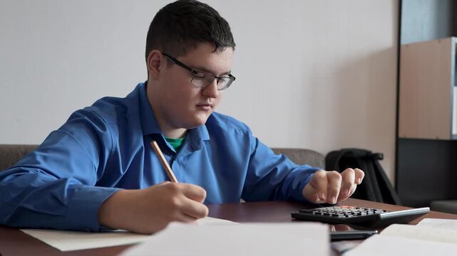 teenager studying at home. boy while doing homework. A male student is tired in class. A schoolboy solves a difficult example while sitting at a table.