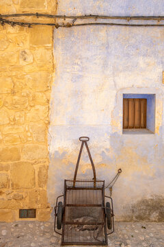 Rustic chair against plaster wall with stone texture in Valderrobres Aragon Spain in daylight showing weathered character and quiet stillness