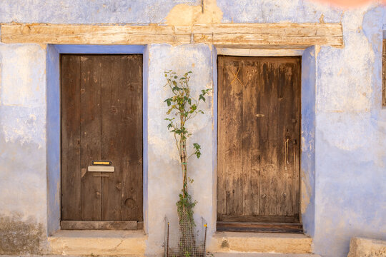 Weathered wooden doors on plaster facade with rustic texture in Valderrobres Aragon Spain captured in daylight for historic street character
