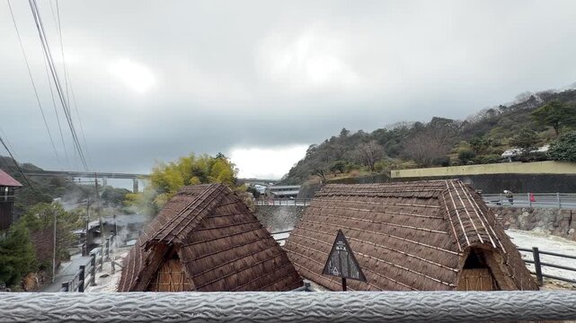 Traditional Japanese onsen landscape with volcanic steam and thatched huts at Myoban Jigoku (4K)