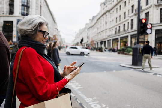 Woman using smartphone while shopping on Regent Street in London