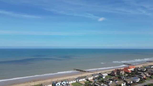 Aerial drone view looking out to North Sea from Walcott Beach with groynes and coastline Norfolk