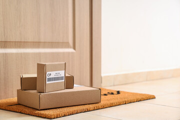Cardboard parcels on mat near door in hallway. Delivery service