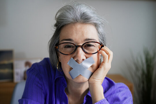 Woman with tape over mouth expressing censorship and protest