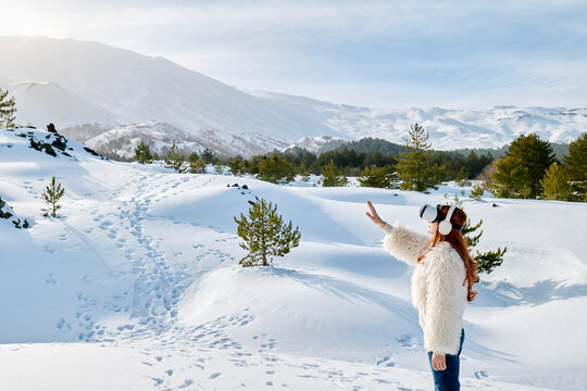 Person using VR headset outdoors in snowy Mount Etna winter landscape