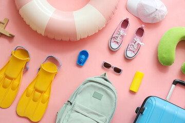 Summer composition with suitcase, inflatable ring, travel pillow, flippers and backpack on pink background © Pixel-Shot