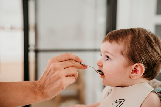 Mother feeding baby with spoon at home showing love and bonding