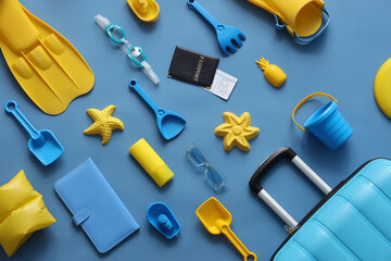 Summer composition with suitcase, beach toys, flippers and passport on blue background © Pixel-Shot