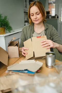 Woman sorting cardboard for recycling at home for sustainability