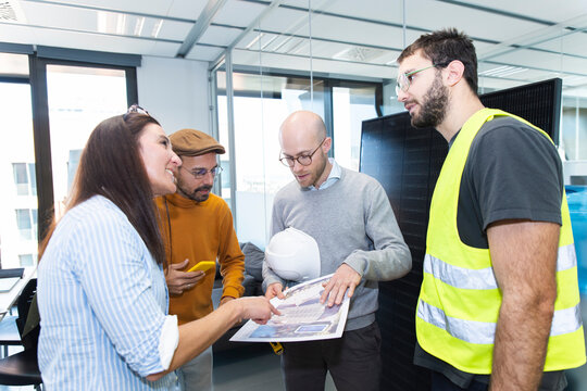 Engineer, installer and clients discussing house plan with solar panel