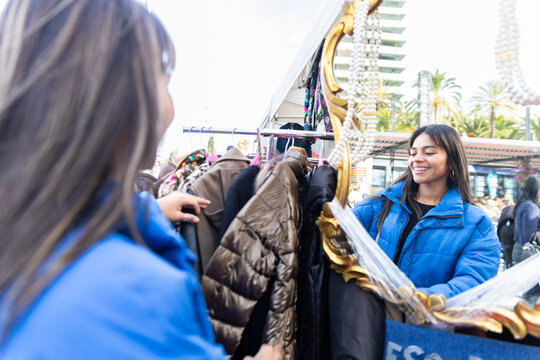 Customer shopping for clothes at flea market in Barcelona reflected in mirror