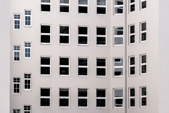 Curved modern architecture building facade with windows forming symmetry pattern in minimal abstract design with clean geometry on white exterior