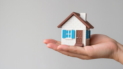 house in hand, financial security and the achievement of owning a home. It captures the concept of real estate within reach. The miniature house represents a new beginning and the protection 