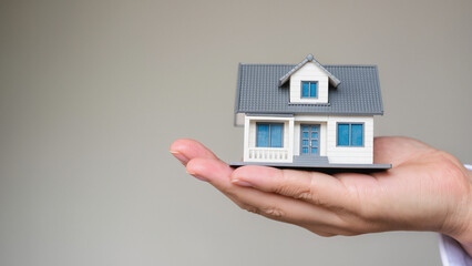 house in hand, financial security and the achievement of owning a home. It captures the concept of real estate within reach. The miniature house represents a new beginning and the protection 