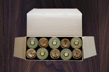 Old hunting shotgun shells in cardboard box, ammunition 12 gauge cartridges. Top view on dark wood surface. Copyspace.