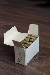 Old hunting shotgun shells in cardboard box, ammunition 12 gauge cartridges on dark wood surface. Copyspace.