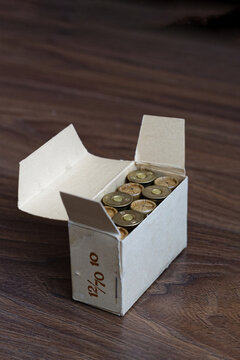 Old hunting shotgun shells in cardboard box, ammunition 12 gauge cartridges on dark wood surface. Copyspace.