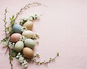 Pastel Easter eggs with white flowers and branches on pink background
