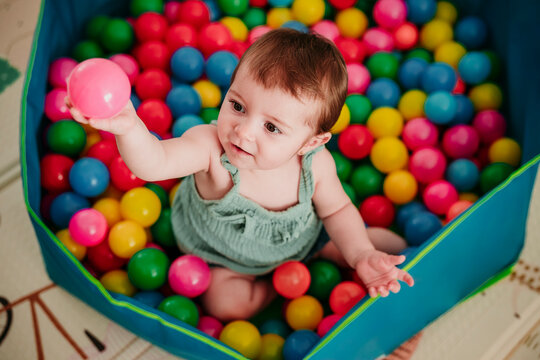 Baby playing with colorful pool balls at home and smiling