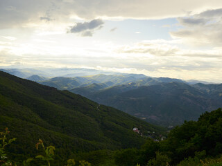 Obraz premium Sunlight Over Rolling Green Mountains and Scenic Valley Landscape