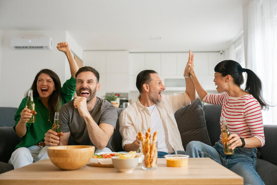 Group of friends celebrating while watching football at home