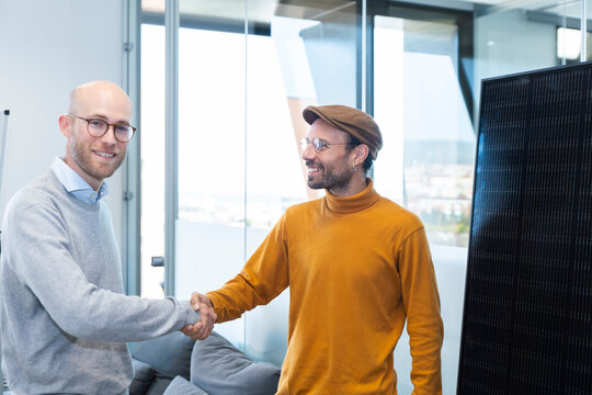 Engineer and client shake hands in office by solar panel