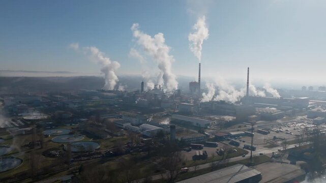 Drone panorama capturing the &Scaron;tět&iacute; industrial skyline with multiple smokestacks and steam plumes, plus the nearby river and bridge fading into morning haze.