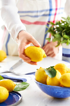 woman hand placing a lemon into a bowl