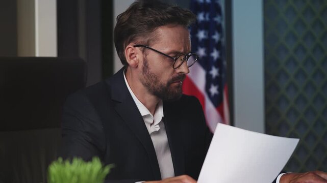 Focused U.S. male government official reviewing documentation in embassy office