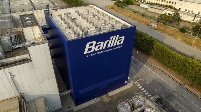 Melfi, Italy - March, 2026: Aerial view of a large, blue industrial building bearing the white Barilla logo. The facility is situated next to a paved road in an industtial area.