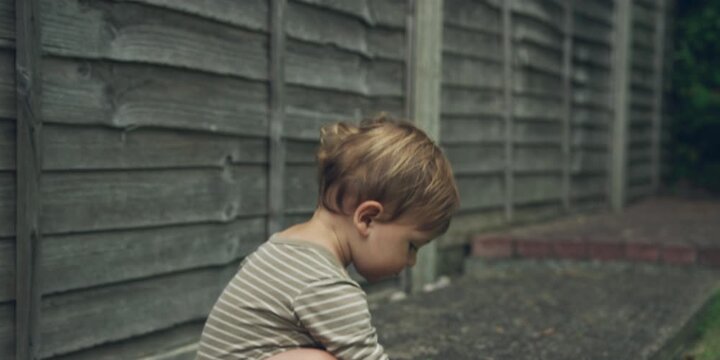 Little toddler playing in a garden in the summer