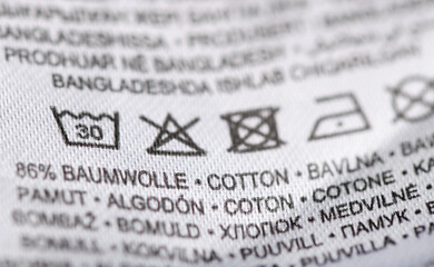 Fototapeta premium Close-up of white garment care label with laundry symbols and fabric content.