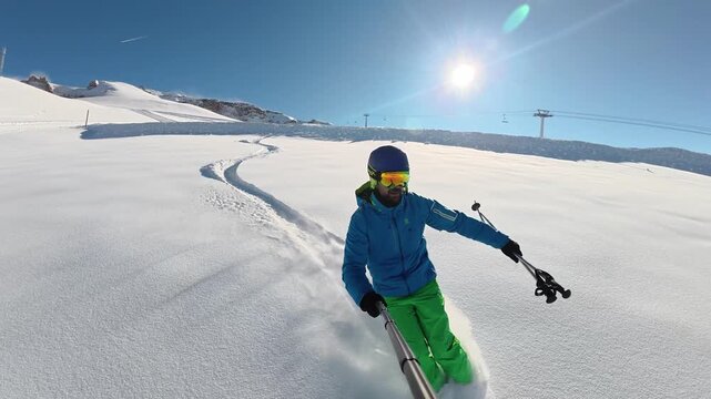 POV style winter action footage of a skier filming himself with an action camera while making first tracks in untouched powder snow on a sunny mountain slope surrounded by pine trees, capturing advent