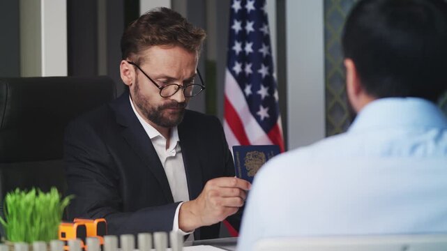 U.S. embassy worker verifying data on laptop, handing British passport to man