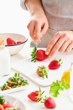 woman hands cutting off the stems of strawberries with a knife