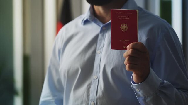Close-up of proud man showing German passport, celebrating citizenship approval