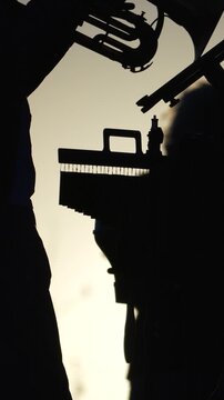 Musicians, trumpet, silhouette performance at golden hour sunset on an outdoor stage, creating a vibrant live music scene. Vertical video