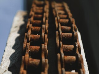 Close-up of a rusty chain with corrosion on a dirty surface, showcasing its texture