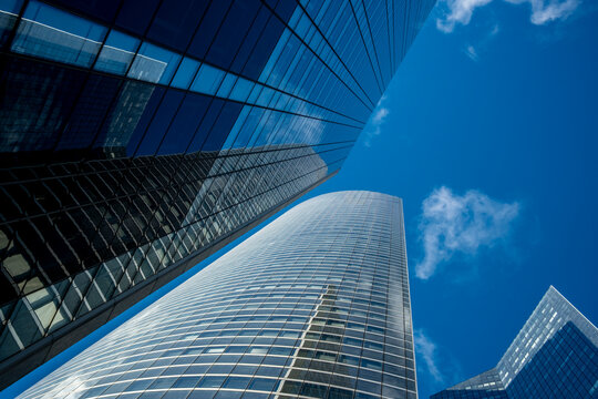 Reflective blue glass skyscraper shot in lowangle perspective in La Defense Paris France with modern architecture lines shaping an urban business district